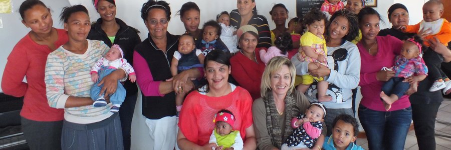 Die groot groep mammas met hul babas, met die beoordelaars, Rochelle de Villiers en Antoinette Louw voor - elk met ‘n baba op die skoot
